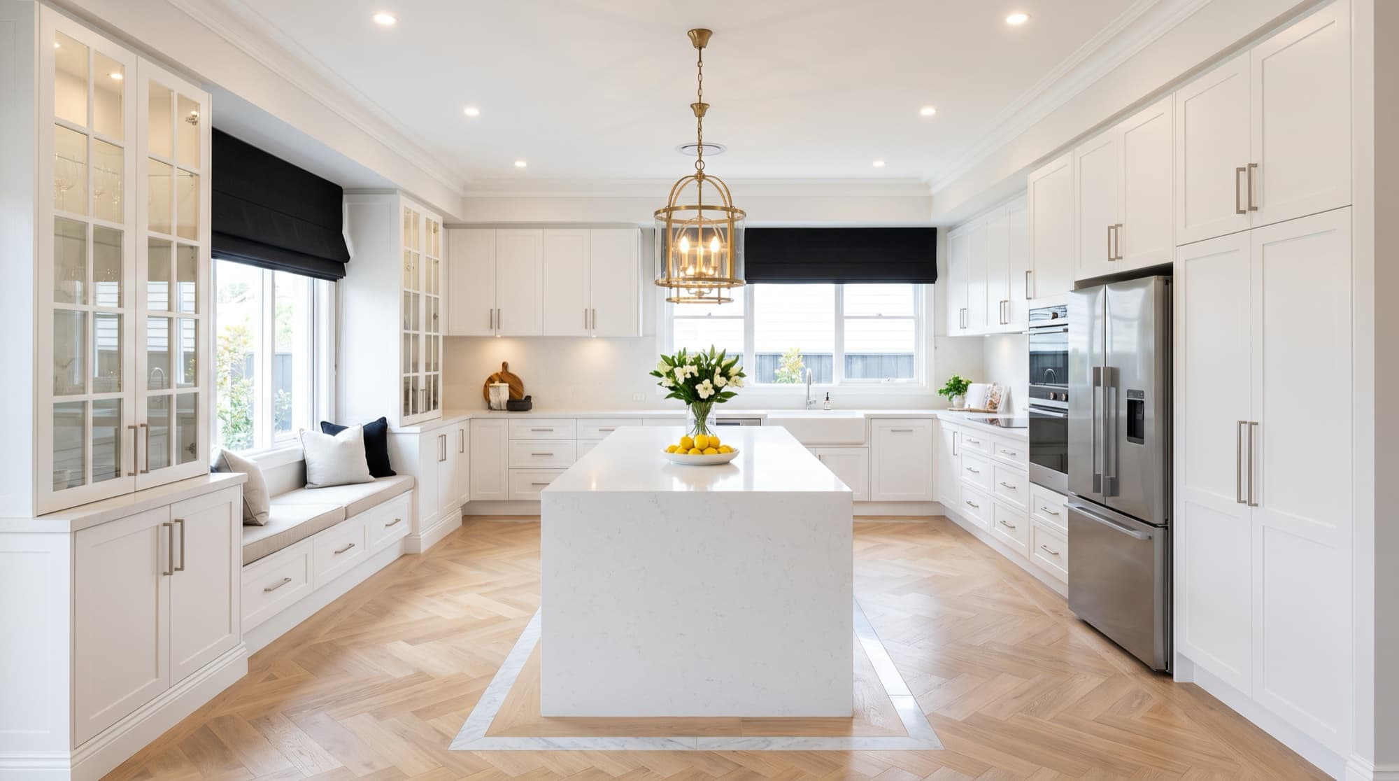 Hamptons-style white shaker kitchen with stone island and glass display cabinets
